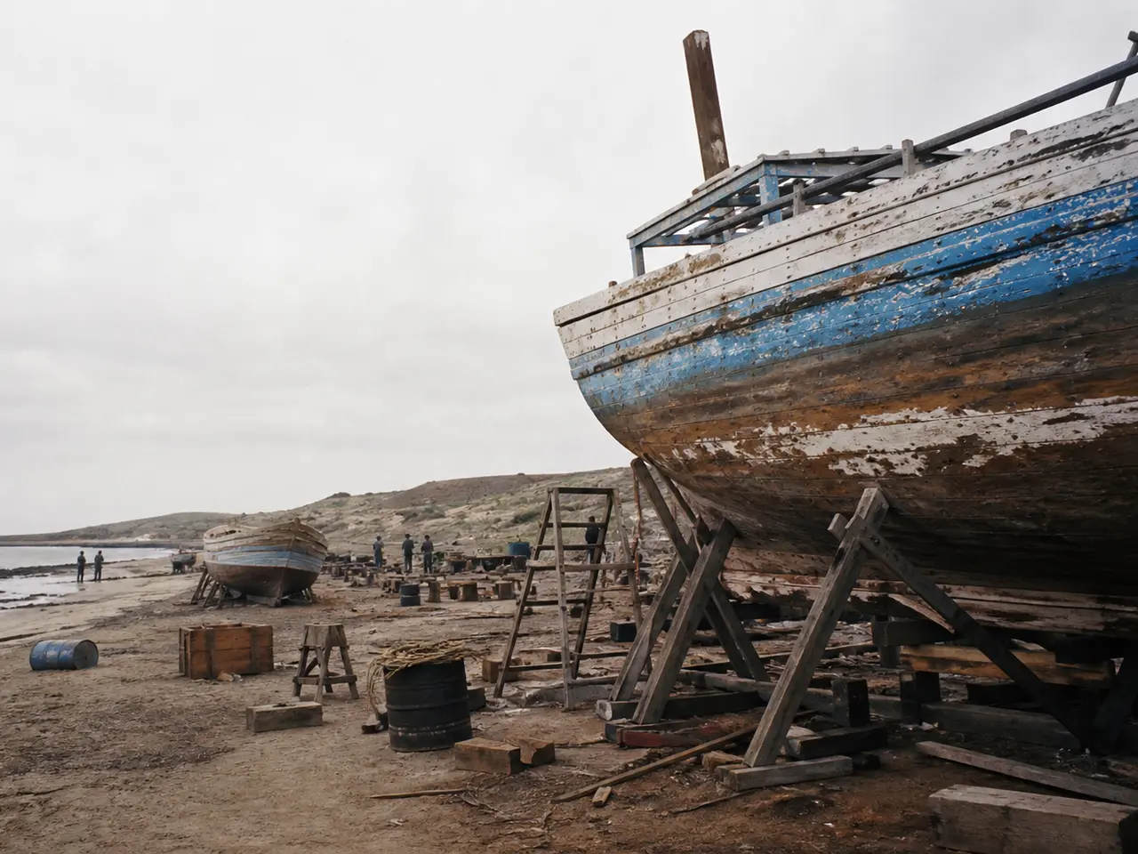 Weathered boats under repair along a fictional overcast coastline