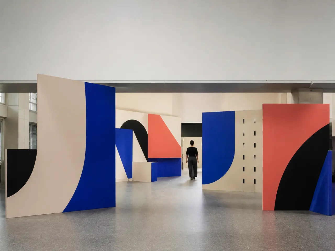 Bold abstract campaign panels installed in a fictional unbranded public hall