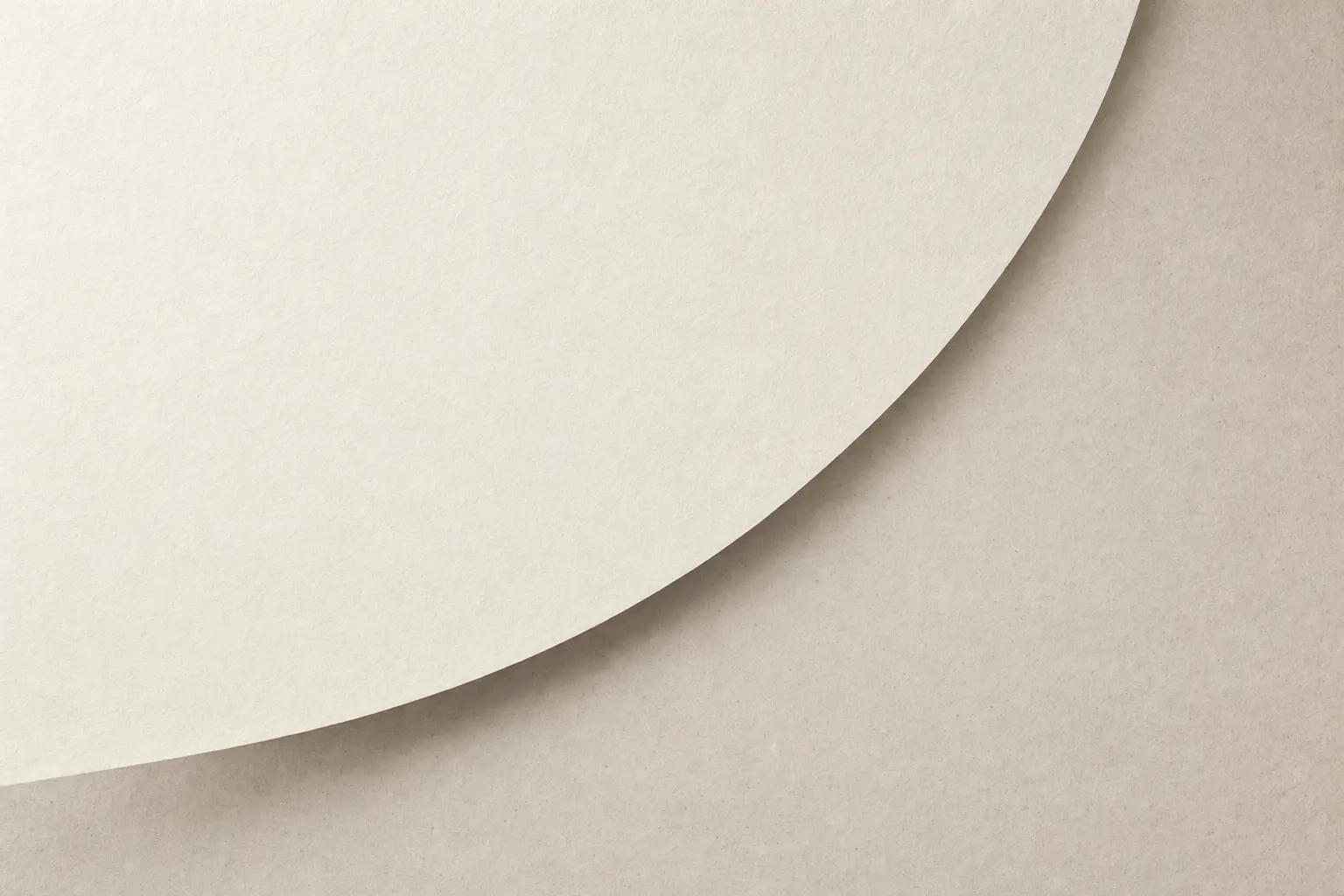 Curved ivory paper edge above a warm neutral surface.